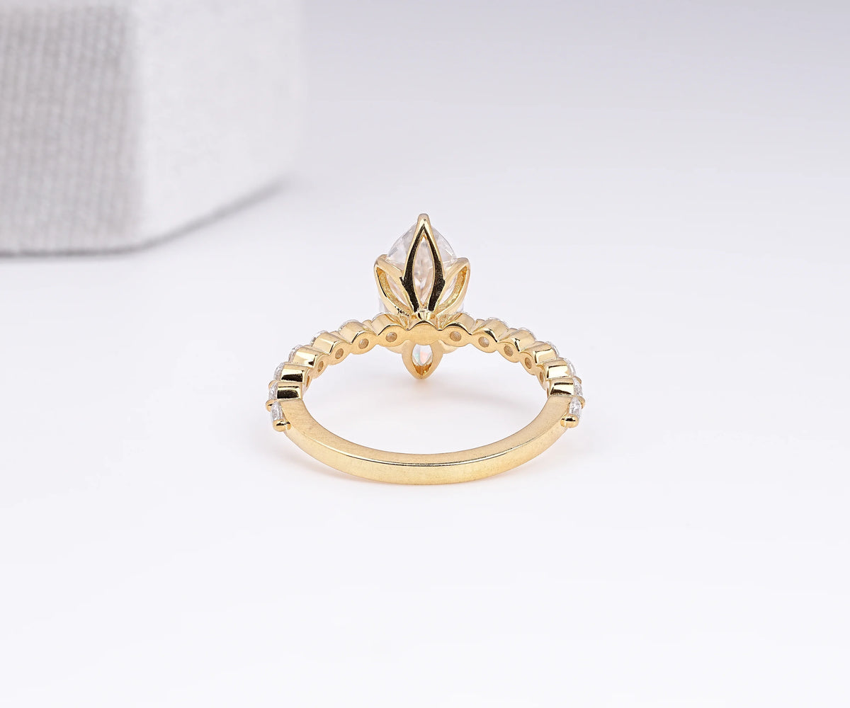 A gold ring with a marquise-cut clear gemstone in a decorative setting, shown on a clean white background.